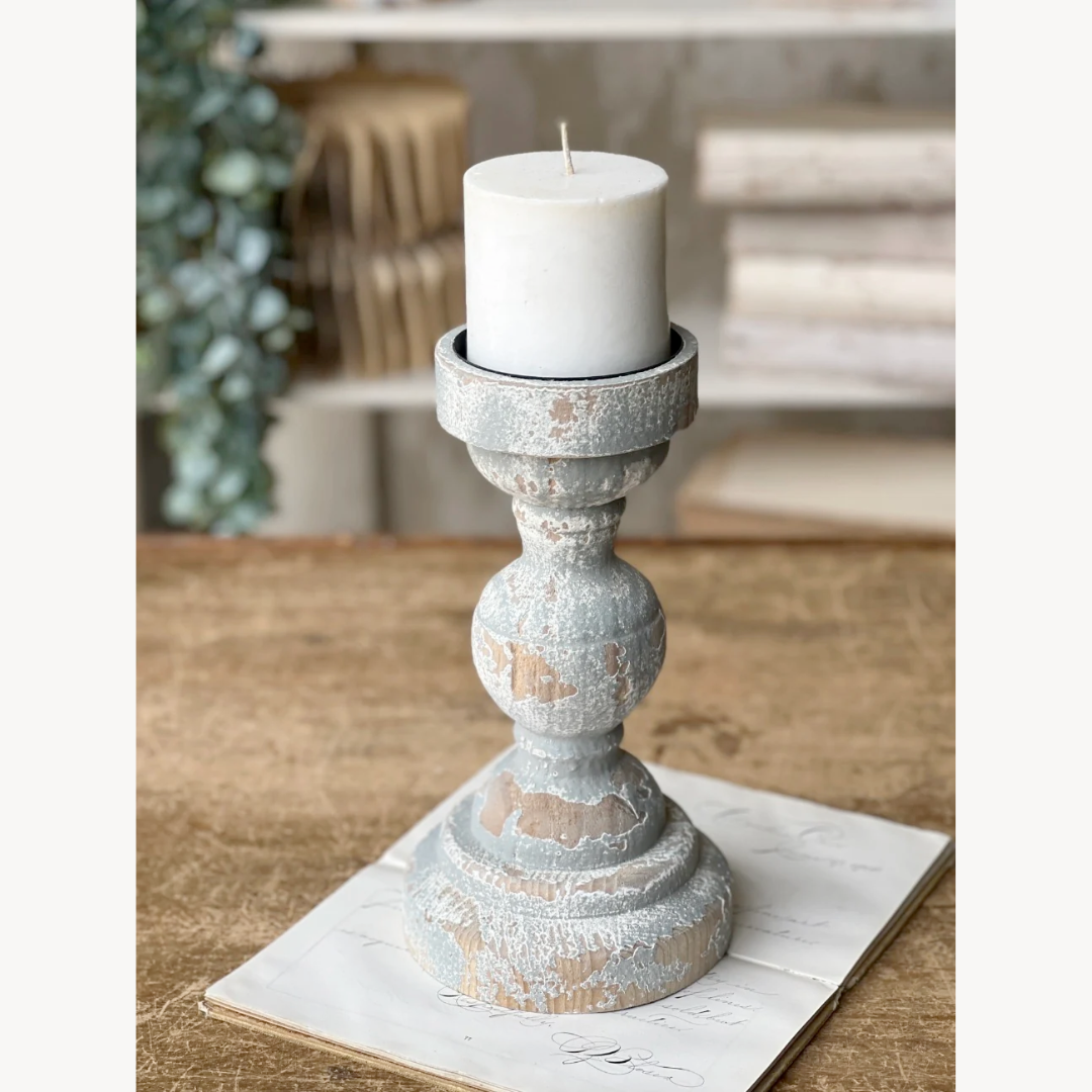 Decorative candle holder with a white candle on a wooden surface