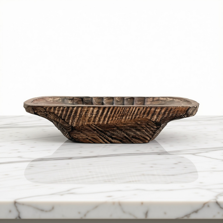 A rustic dark brown wooden dough bowl with a ribbed exterior and scalloped rim, displayed on a white marble surface against a white background.
