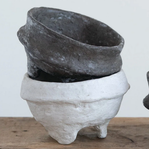 Three paper maché footed bowls on a wooden surface with a plain background