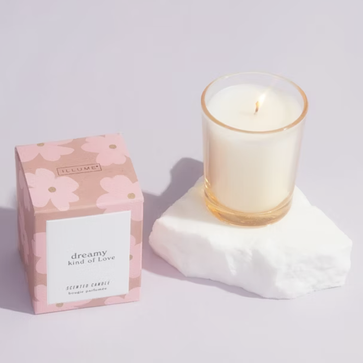 Candle with packaging labeled 'dreamy kind of love' on a light background