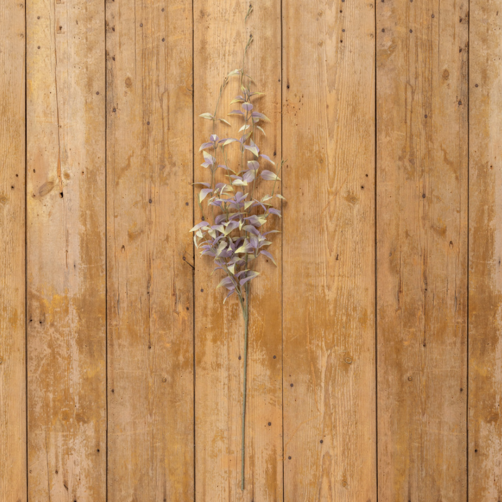 Artificial purple flower branch on a wooden surface