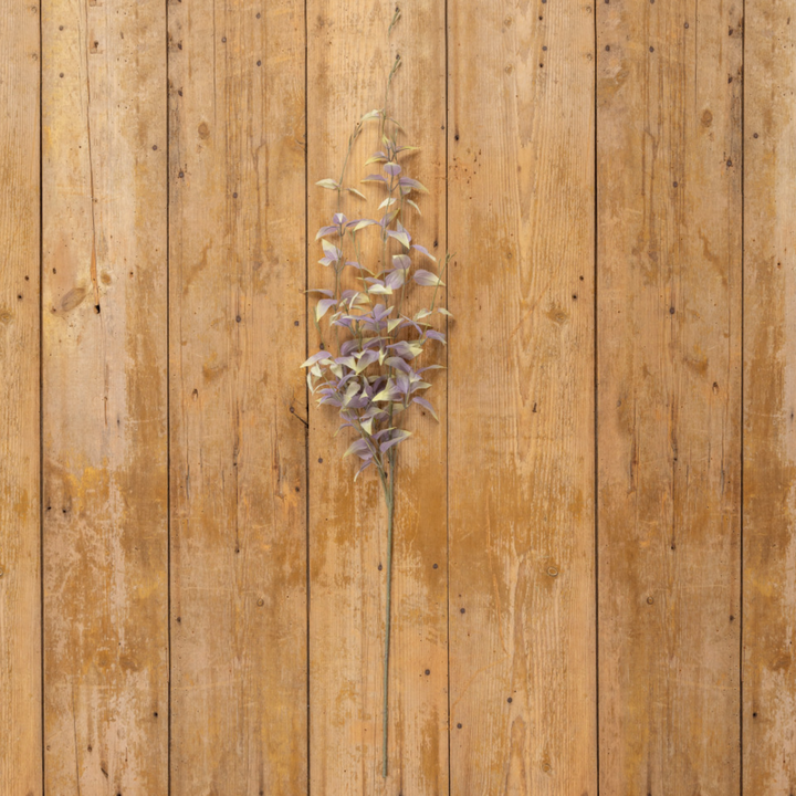 Artificial purple flower branch on a wooden surface