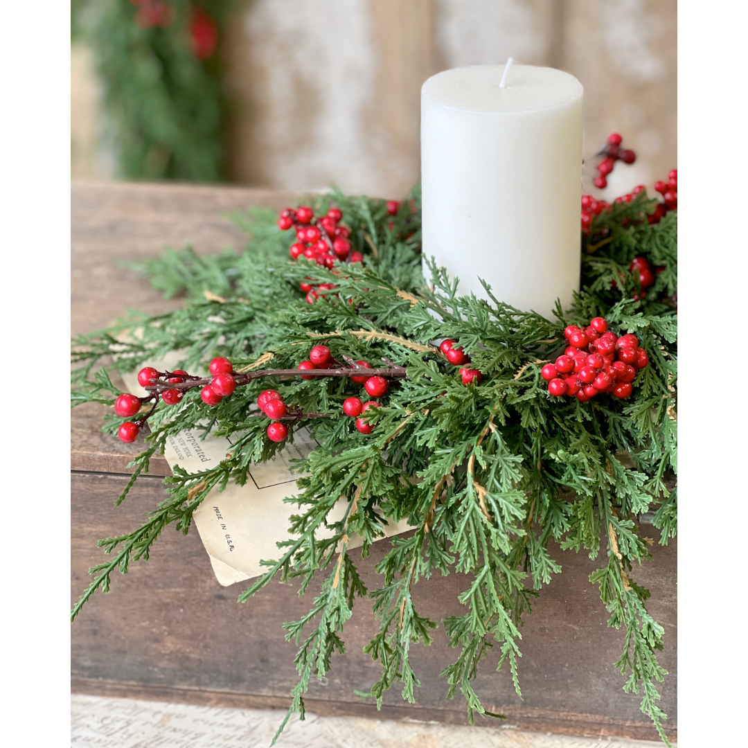 Decorative wreath with greenery and red berries on a wooden surface