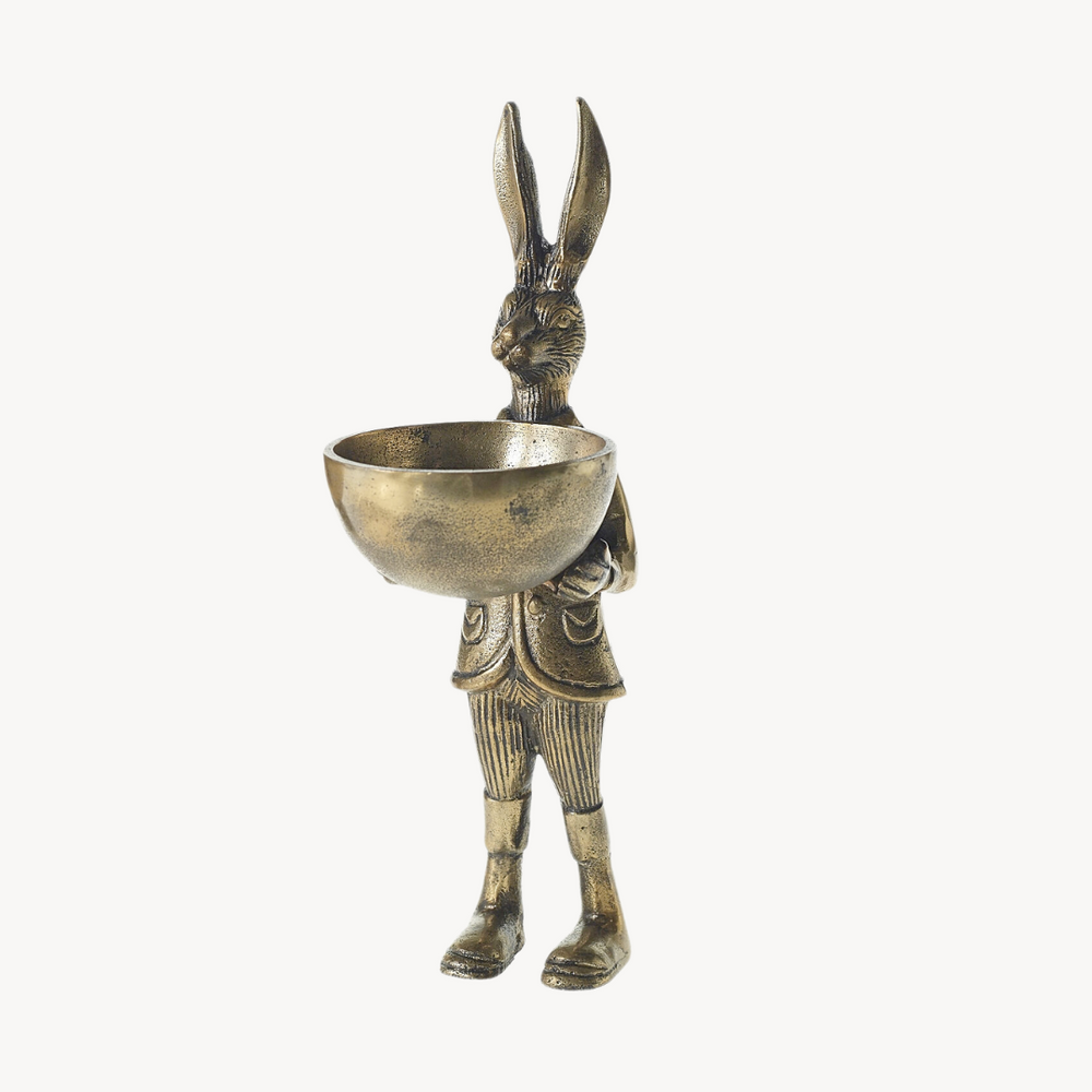 A brass figurine of a rabbit standing upright holding a bowl, with an antiqued gold finish.