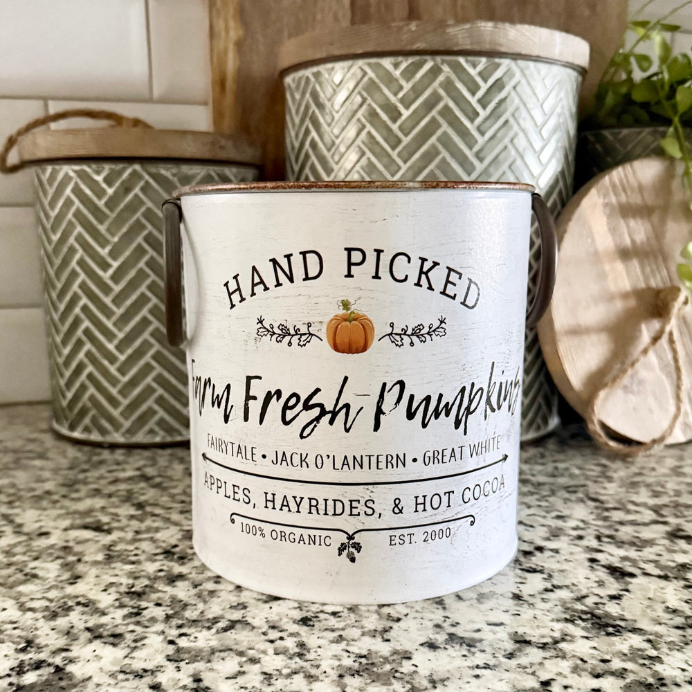 Metal bucket with 'Hand Picked Farm Fresh Pumpkins' text on a granite countertop.