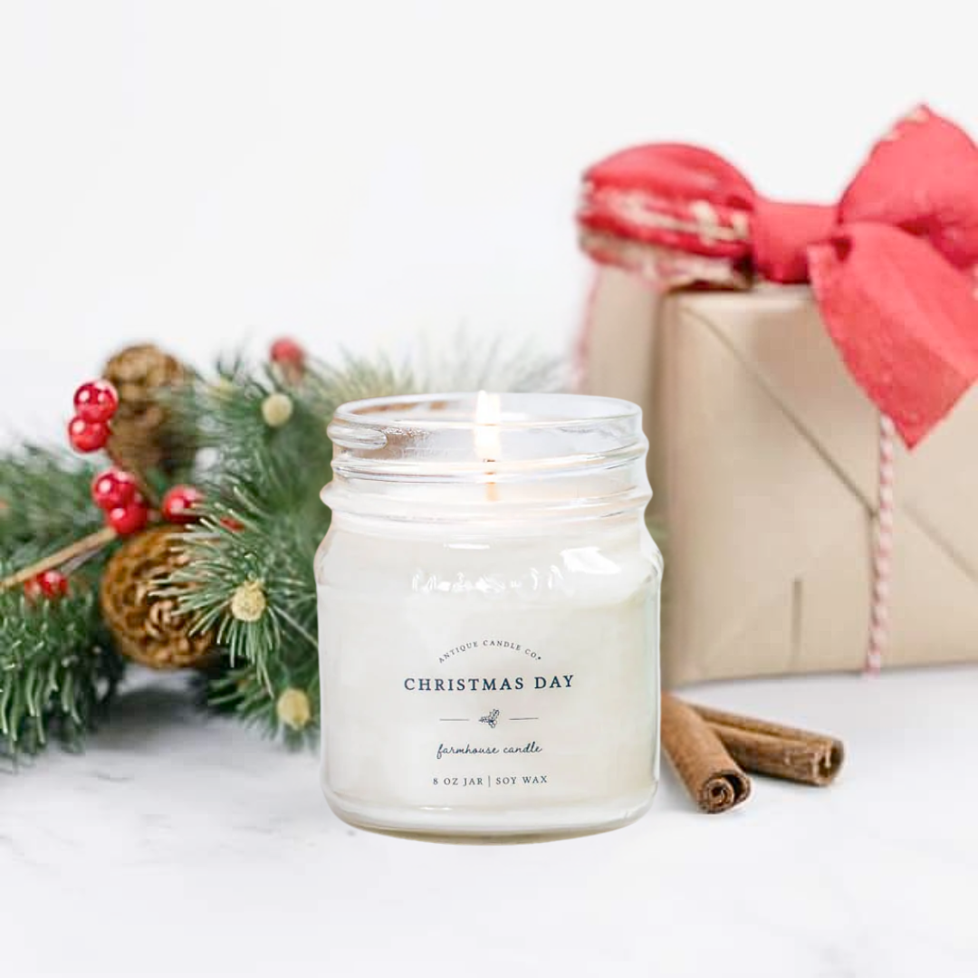 Farmhouse Candle labeled 'Christmas Day' with festive decorations including a gift and cinnamon sticks on a white background