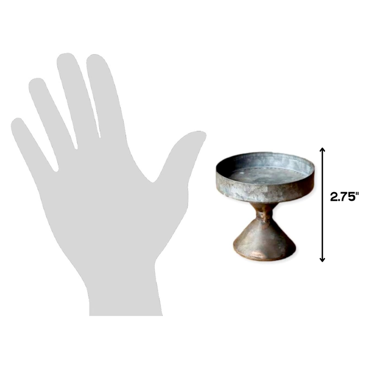 Small decorative metal stand next to a hand for scale on a white background