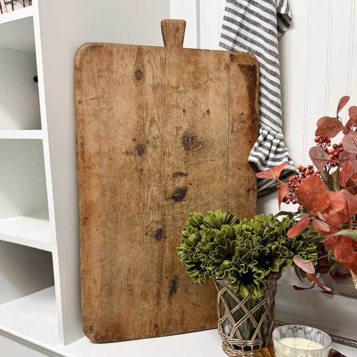 Vintage wooden cutting board on a white surface with decorative elements
