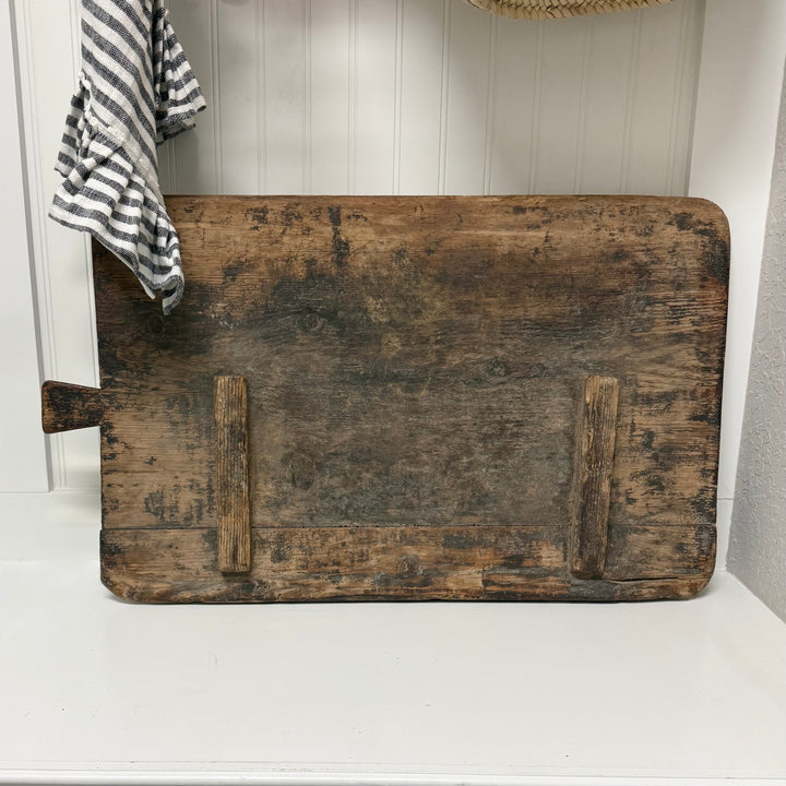 Vintage wooden cutting board on a white surface with a striped towel in the background.