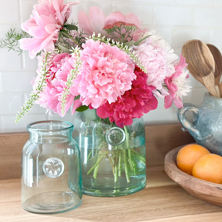 Clear glass mason jars with pink flowers on a wooden surface