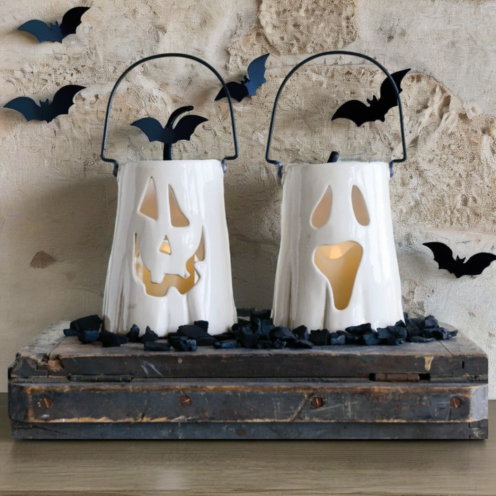 Two Halloween-themed paper lanterns with bat designs on a rustic wooden platform.