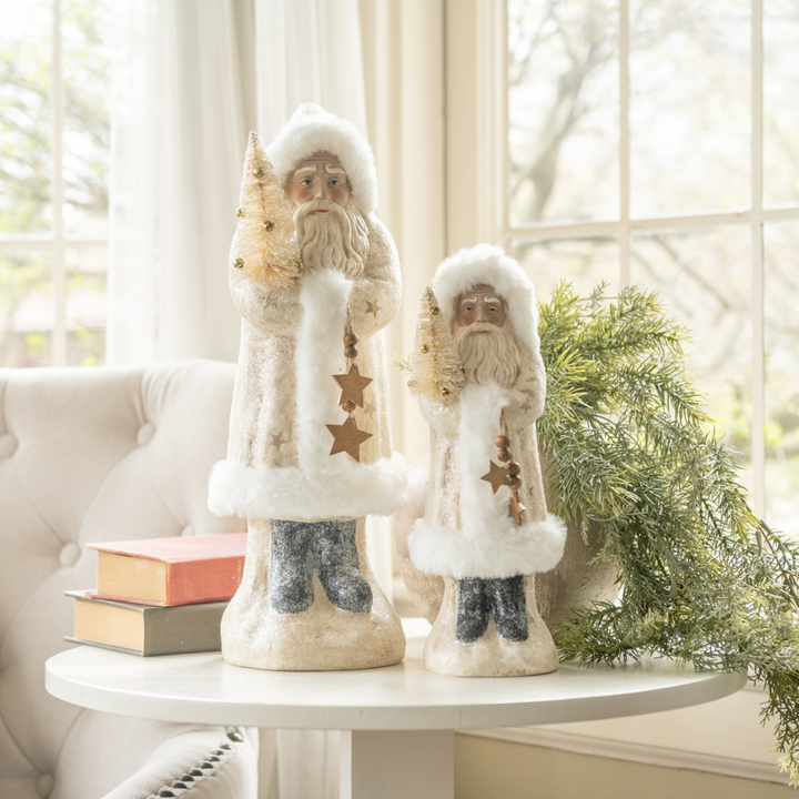 Two decorative Santa figures on a table with a soft, blurred background