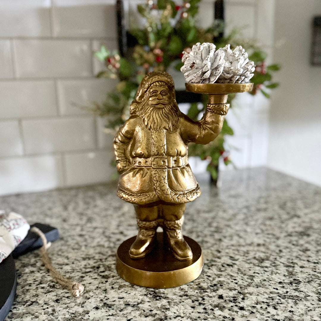 Gold Santa Claus figurine holding a tray with decorative items on a kitchen counter.