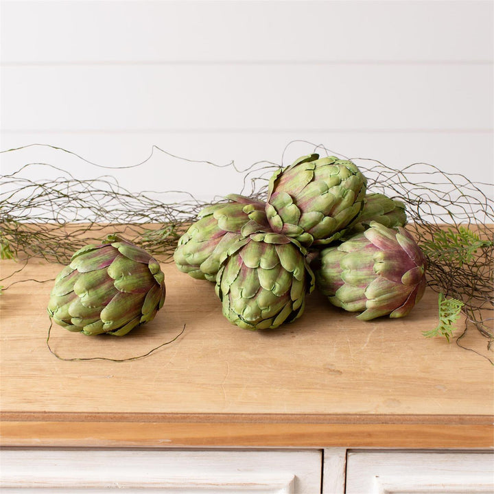 Faux Artichokes on a wooden surface with a neutral background