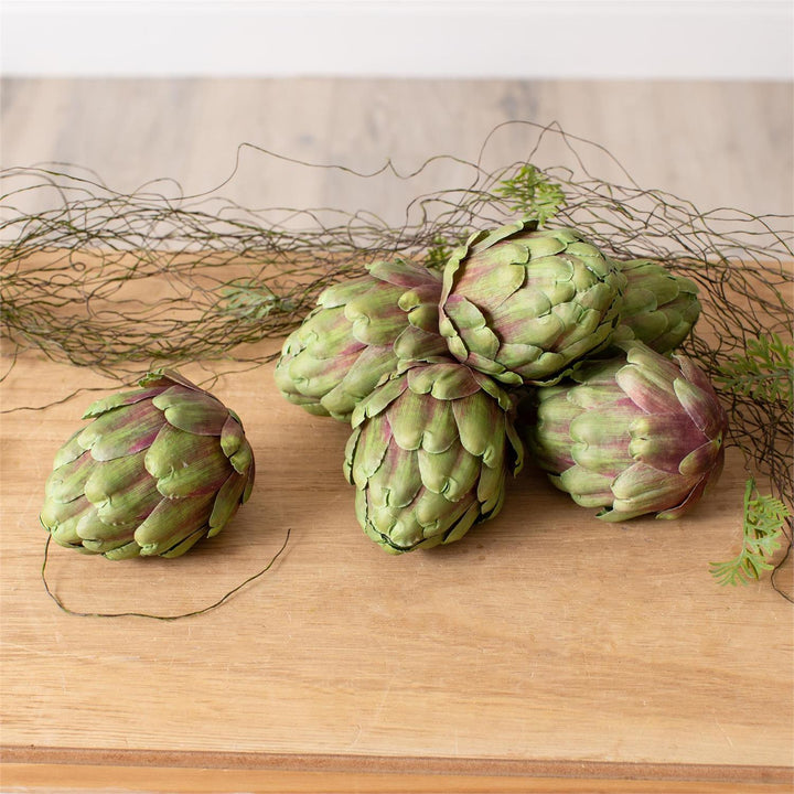 Artificial Artichokes on a wooden surface with decorative branches