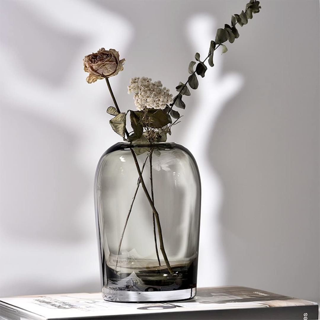 Clear glass vase with flowers on a light gray background