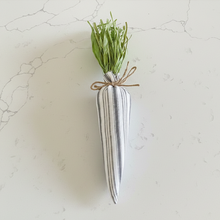 Decorative carrot-shaped vase with green grass on a light gray background