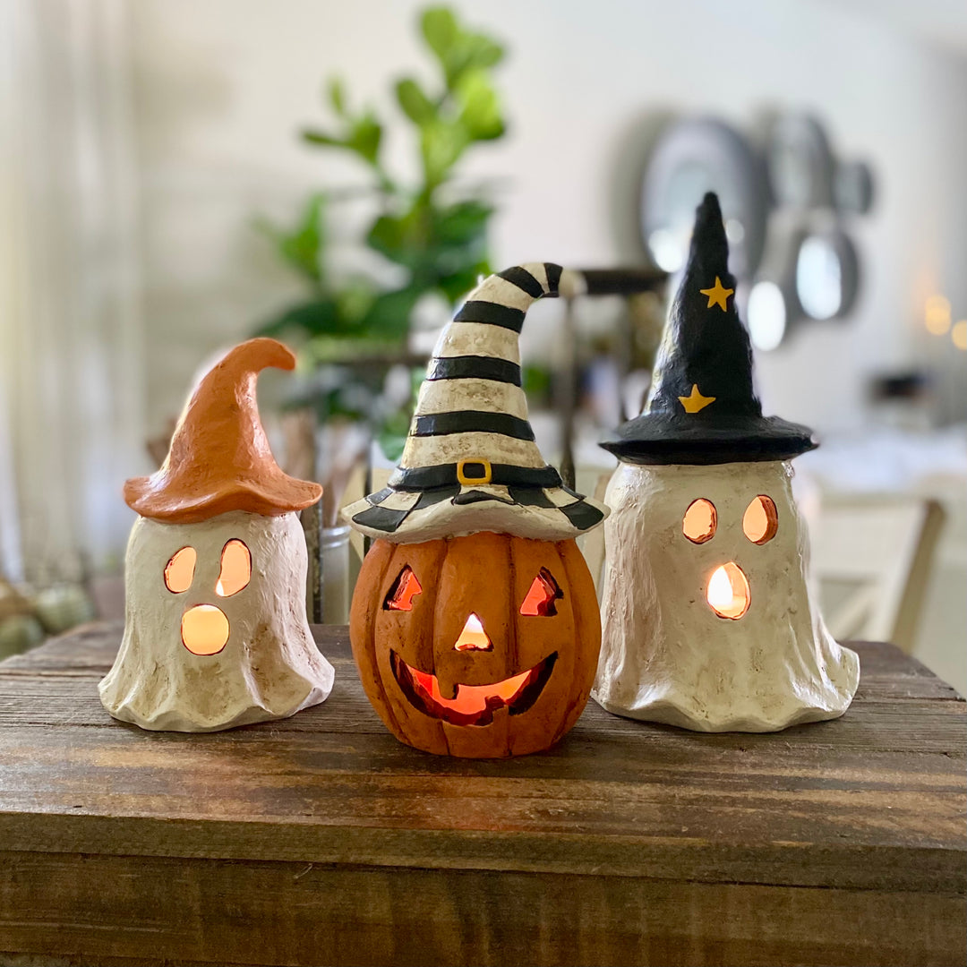 Three Halloween-themed ceramic lights with witch hats on a wooden surface.