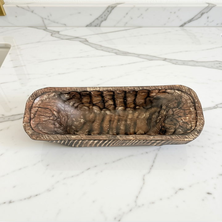 A rectangular carved wooden bowl with a ribbed, textured interior and rounded corners, shown on a white marble surface.