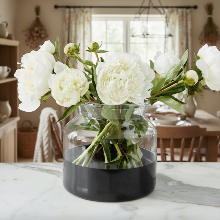 Clear vase with white flowers on a marble surface in a home setting