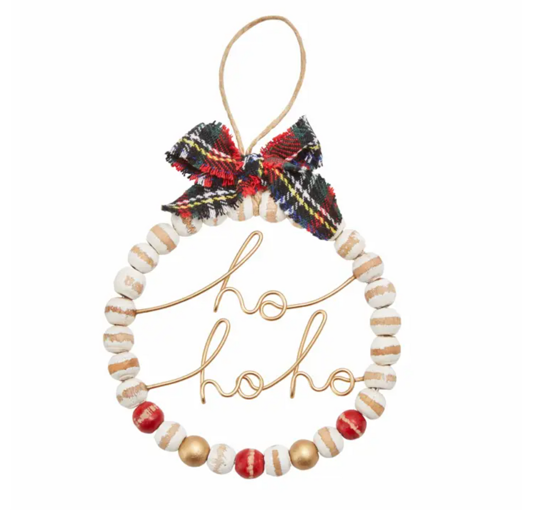 A round beaded ornament with a red and green plaid bow and the word 'ho ho ho' in the center.