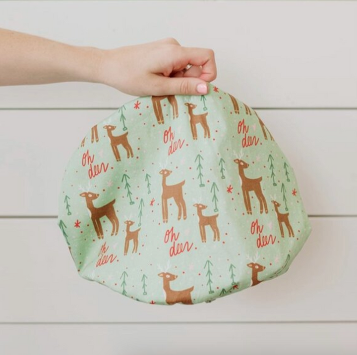 Holiday Fabric bowl cover with deer pattern held by a hand on a light wooden background