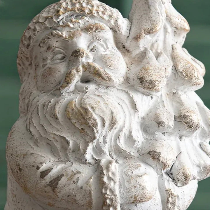 Stone sculpture of a bearded Santa figurine holding a Christmas tree