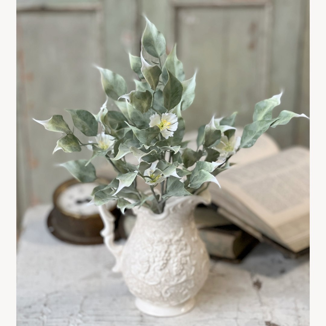 White textured vase with green plant on a textured surface