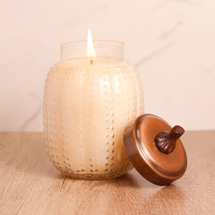 Scented candle in a textured glass jar with a metal lid 