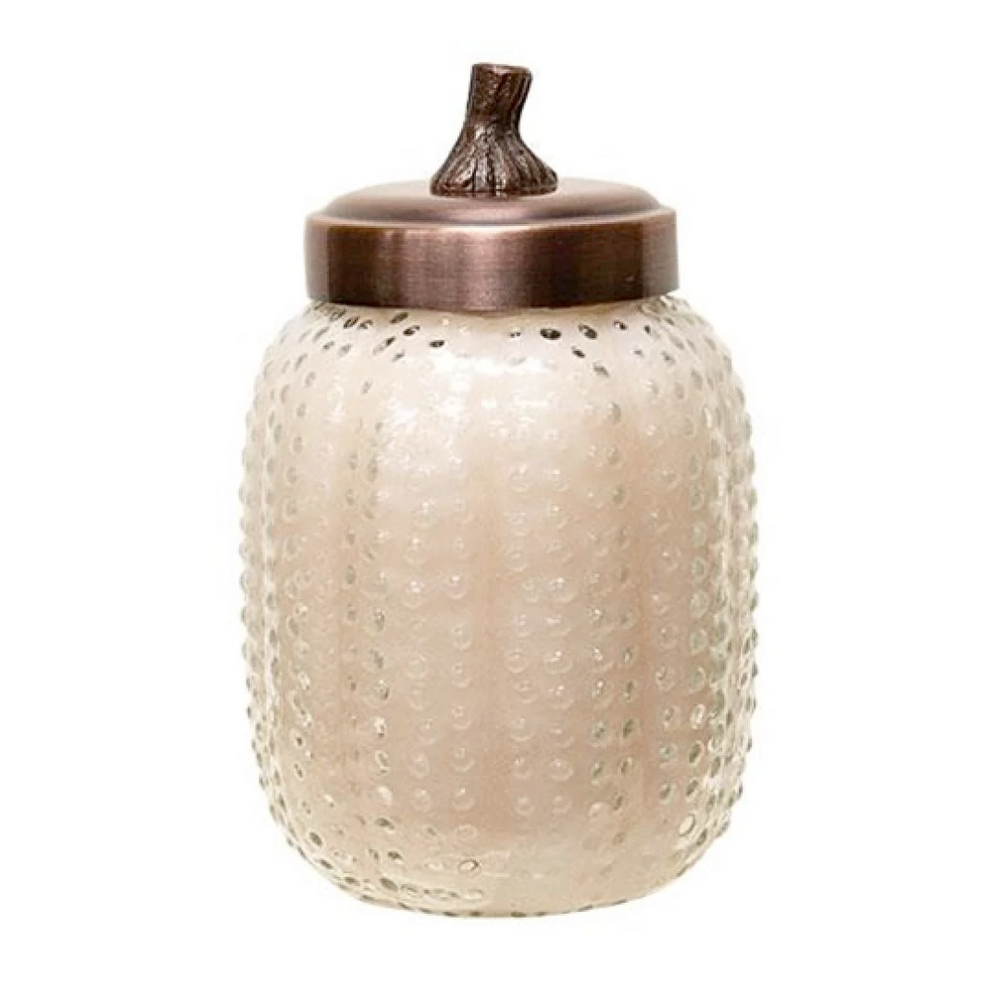 Pumpkin scented glass jar with textured surface and bronze lid on a white background