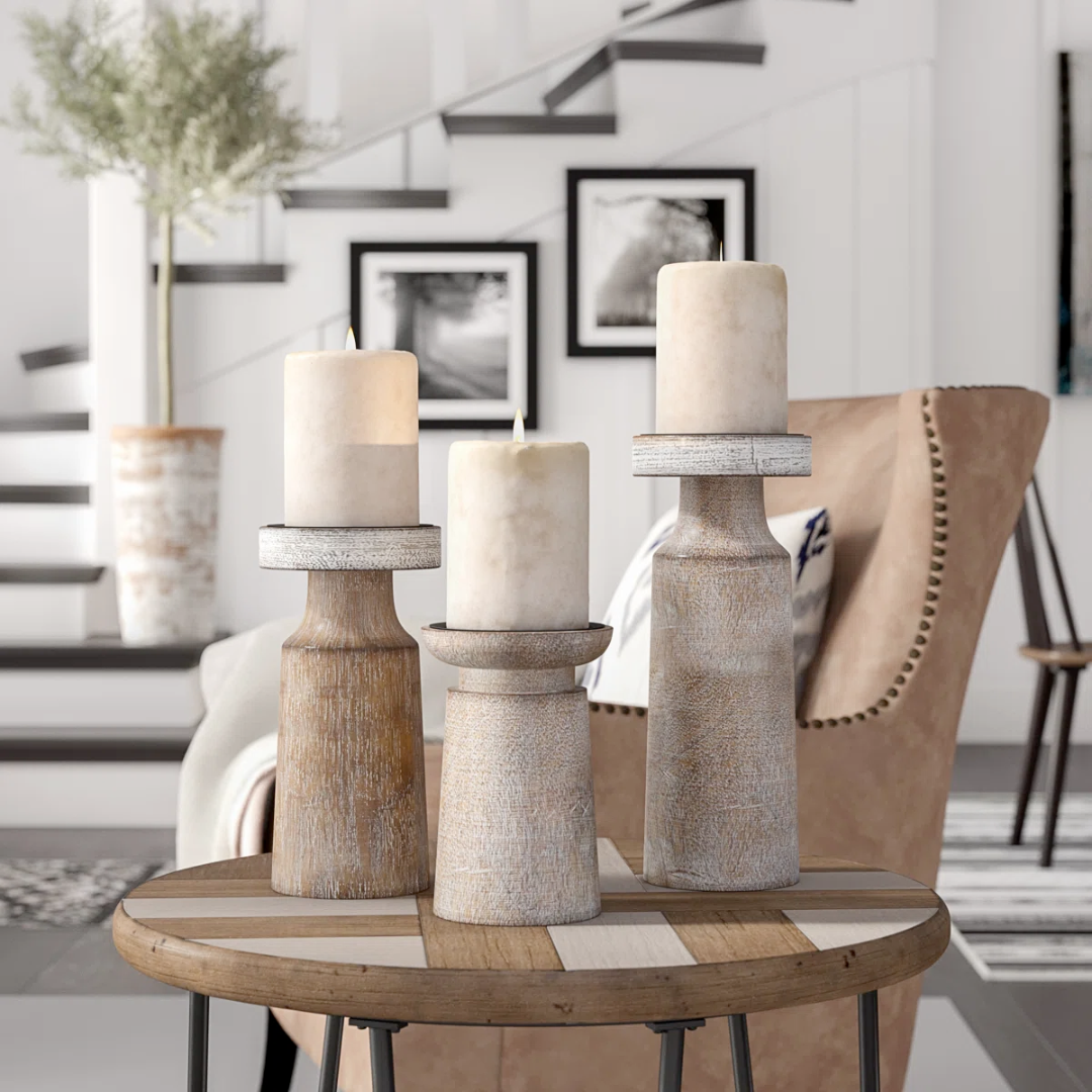Three whitewashed mango wood candle holders with iron candle plates on a round wooden table