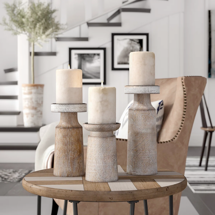 Three whitewashed mango wood candle holders with iron candle plates on a round wooden table