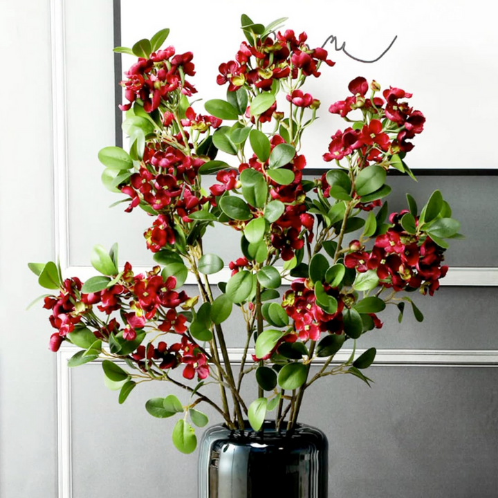 Artificial burgundy flower blooms and green leaf floral arrangement 