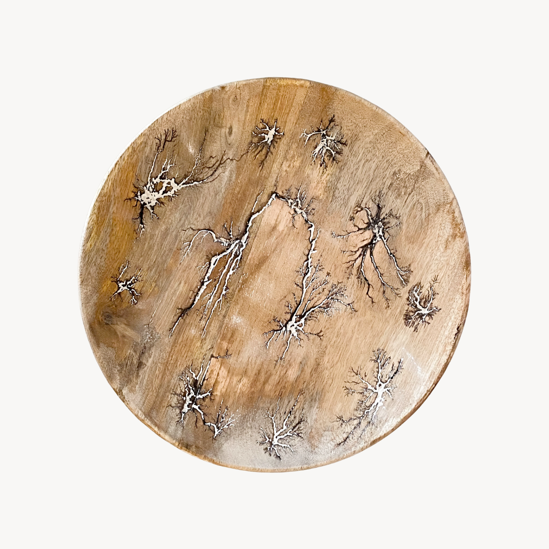 Round wooden crackle finish tray with star-like patterns on a white background
