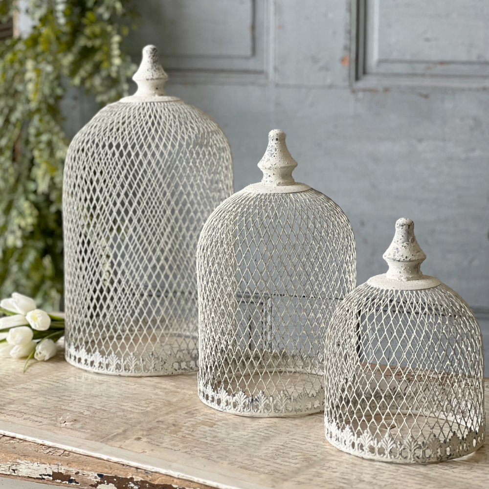 Three decorative mesh domes on a wooden surface with a gray wall background