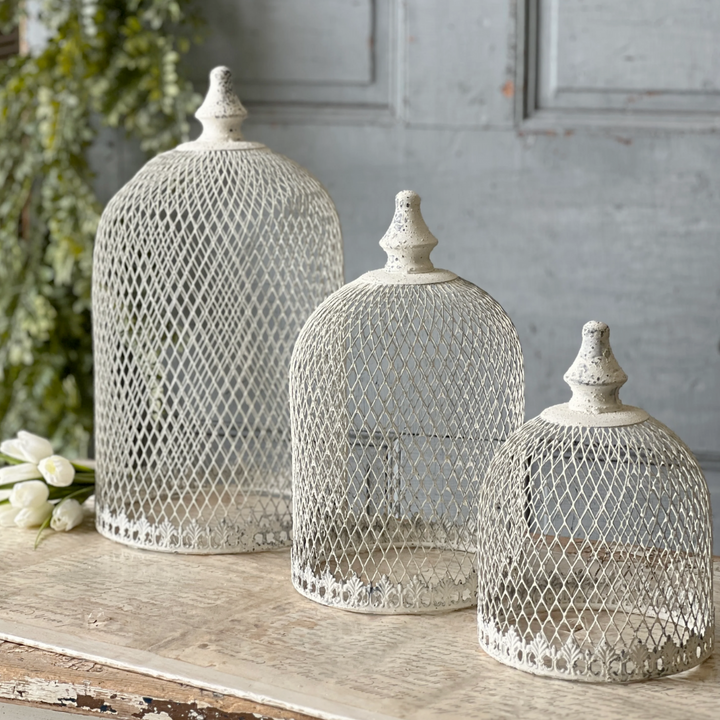 Three decorative mesh domes on a wooden surface with a gray wall background