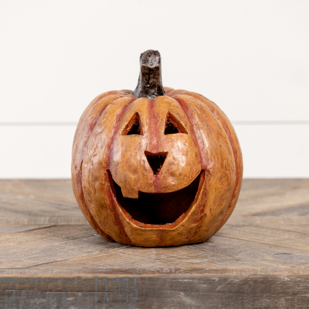 Carved orange paper mache pumpkin with a smiling face on a wooden surface