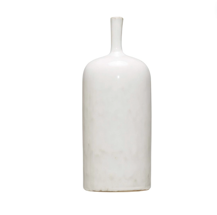 Three white stoneware vases of varying sizes arranged on a wooden surface, with the topmost vase containing a sprig of greenery.