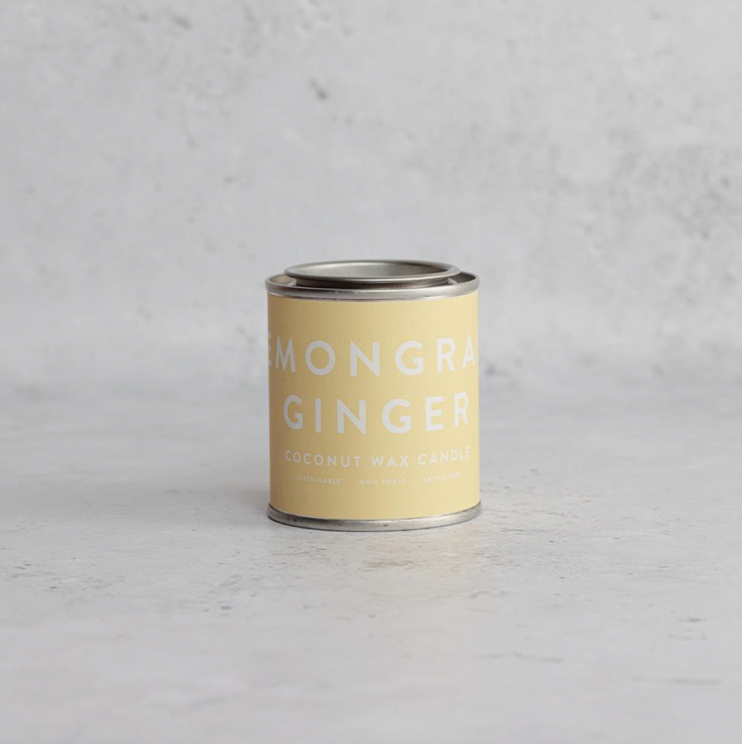 A collection of Conscious Coconut Wax Candles in various colors, displayed in reusable and recyclable paint tins.