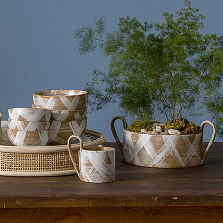 Decorative woven baskets and a pot with plants on a wooden surface against a blue wall.