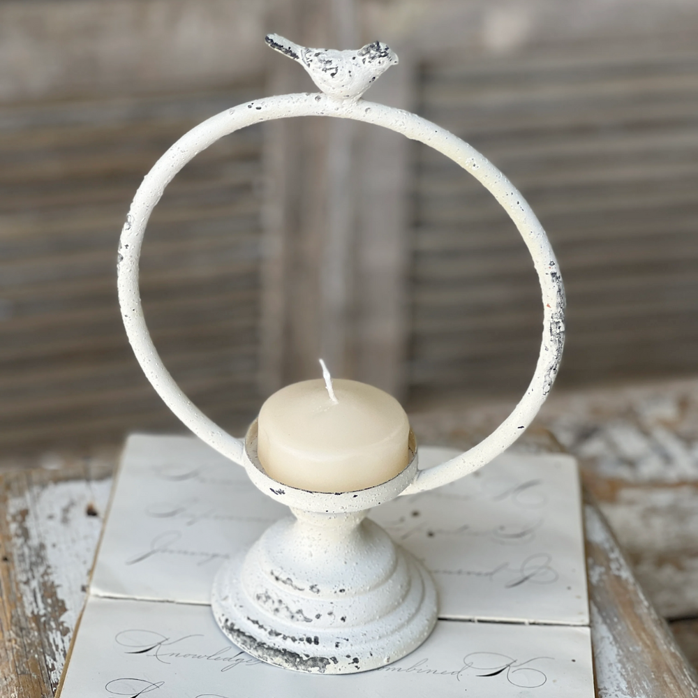 Decorative candle holder with a bird on top on a rustic wooden surface