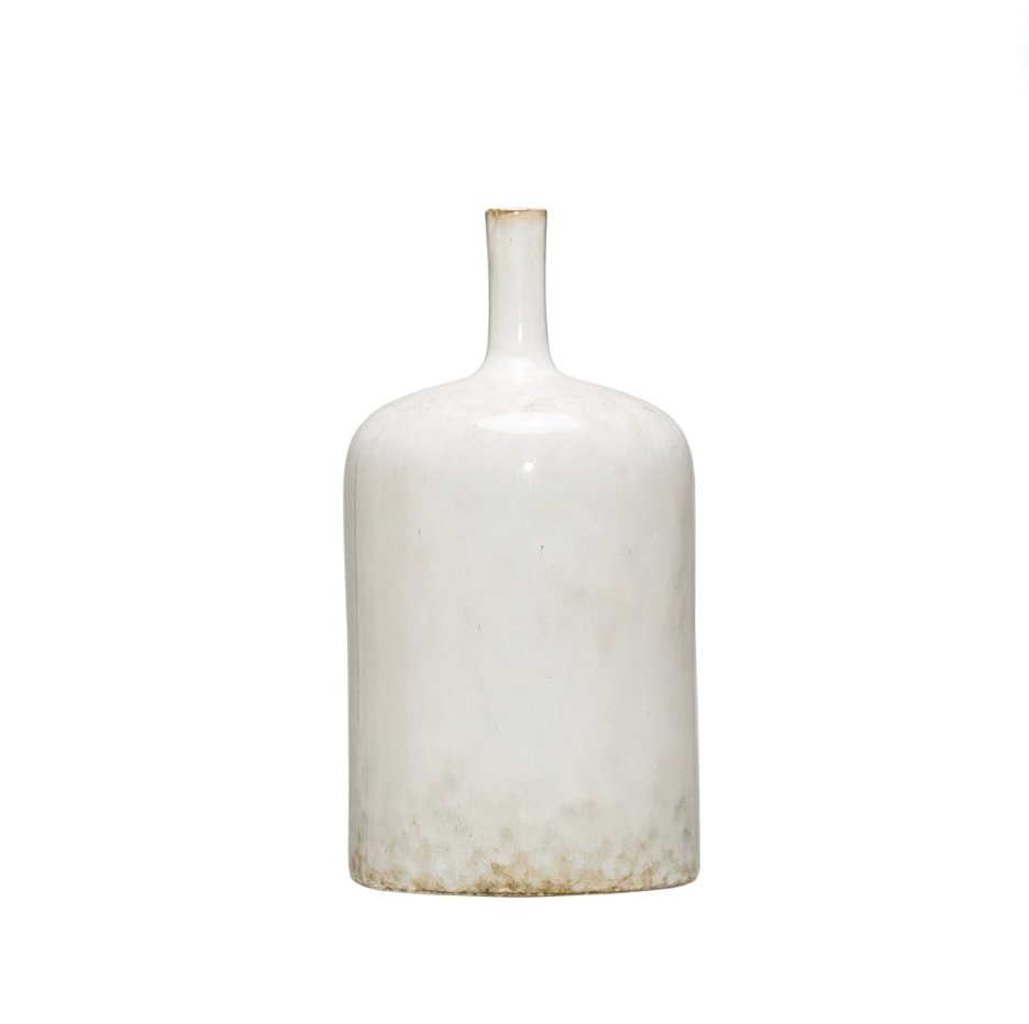 Three white stoneware vases of varying sizes arranged on a wooden surface, with the topmost vase containing a sprig of greenery.