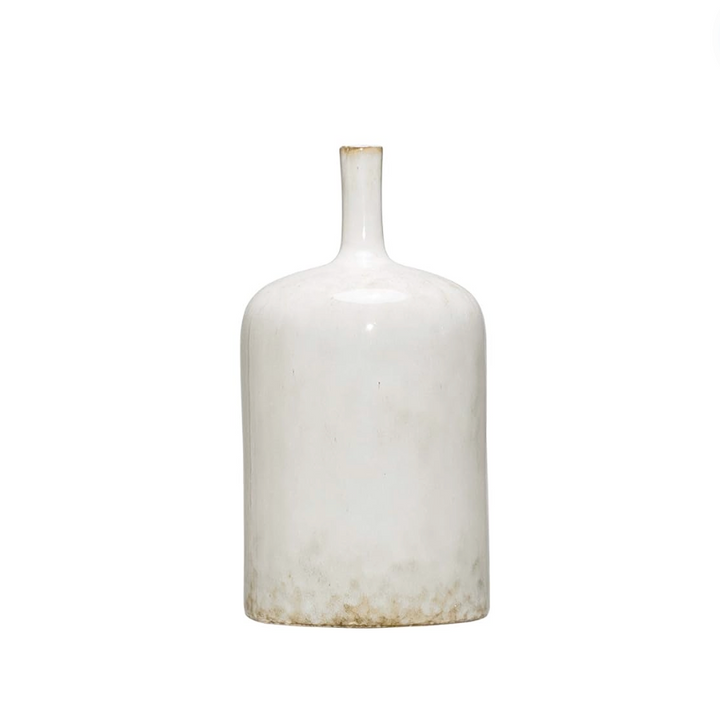 Three white stoneware vases of varying sizes arranged on a wooden surface, with the topmost vase containing a sprig of greenery.