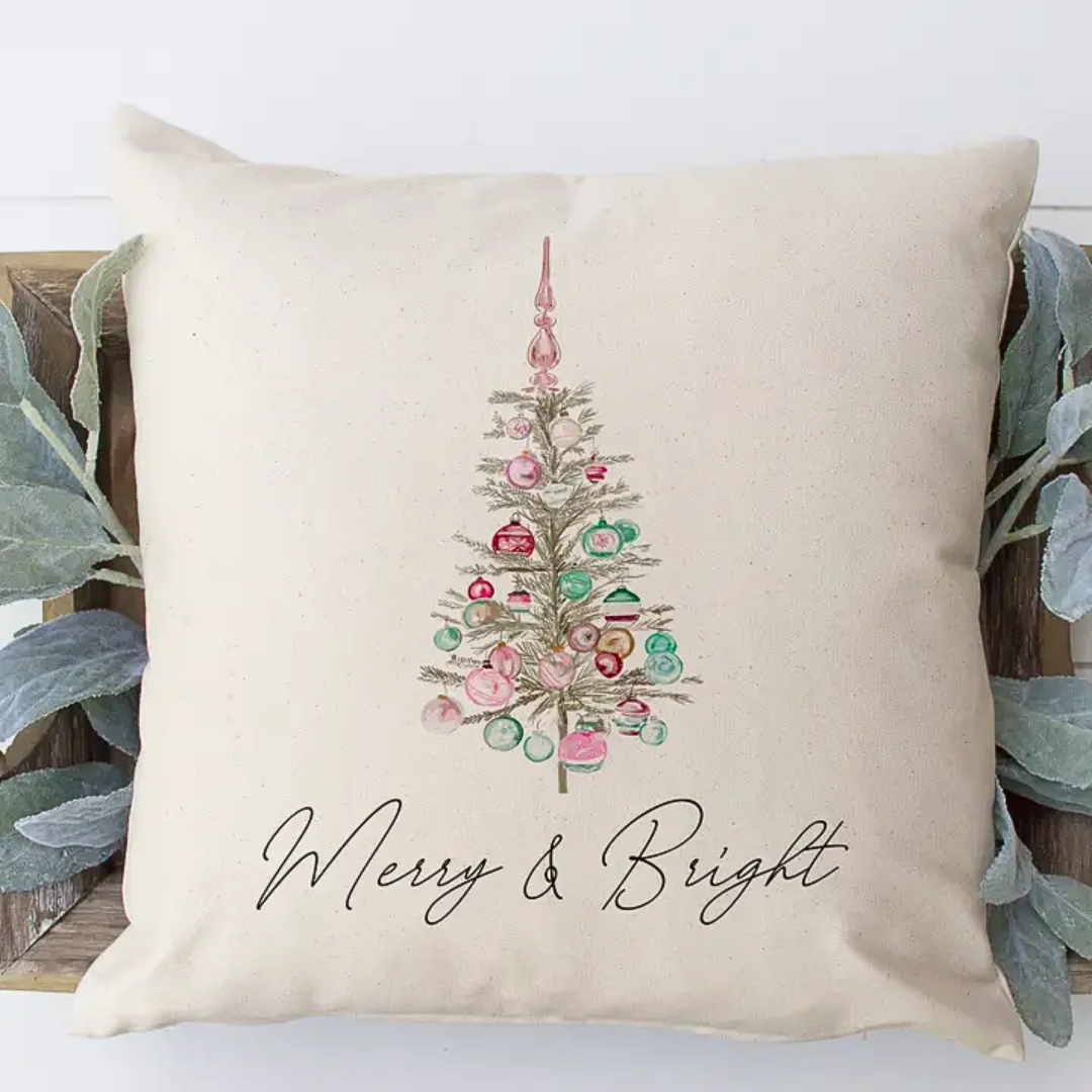 Decorative pillow with a Christmas tree design and 'Merry & Bright' text on a beige background.