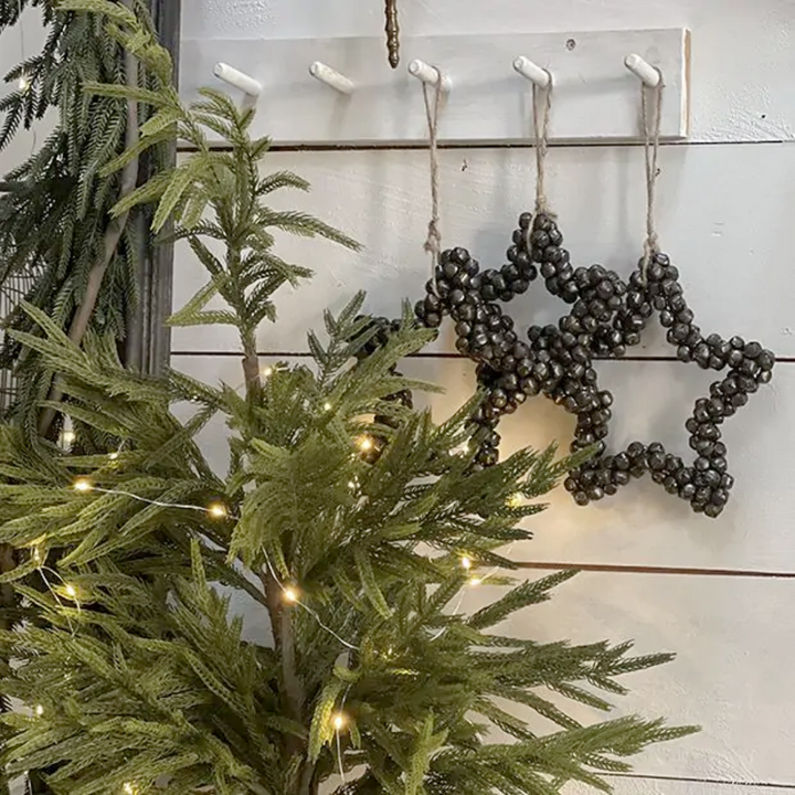 Decorative star-shaped ornaments hanging on a wall next to a Christmas tree with lights.