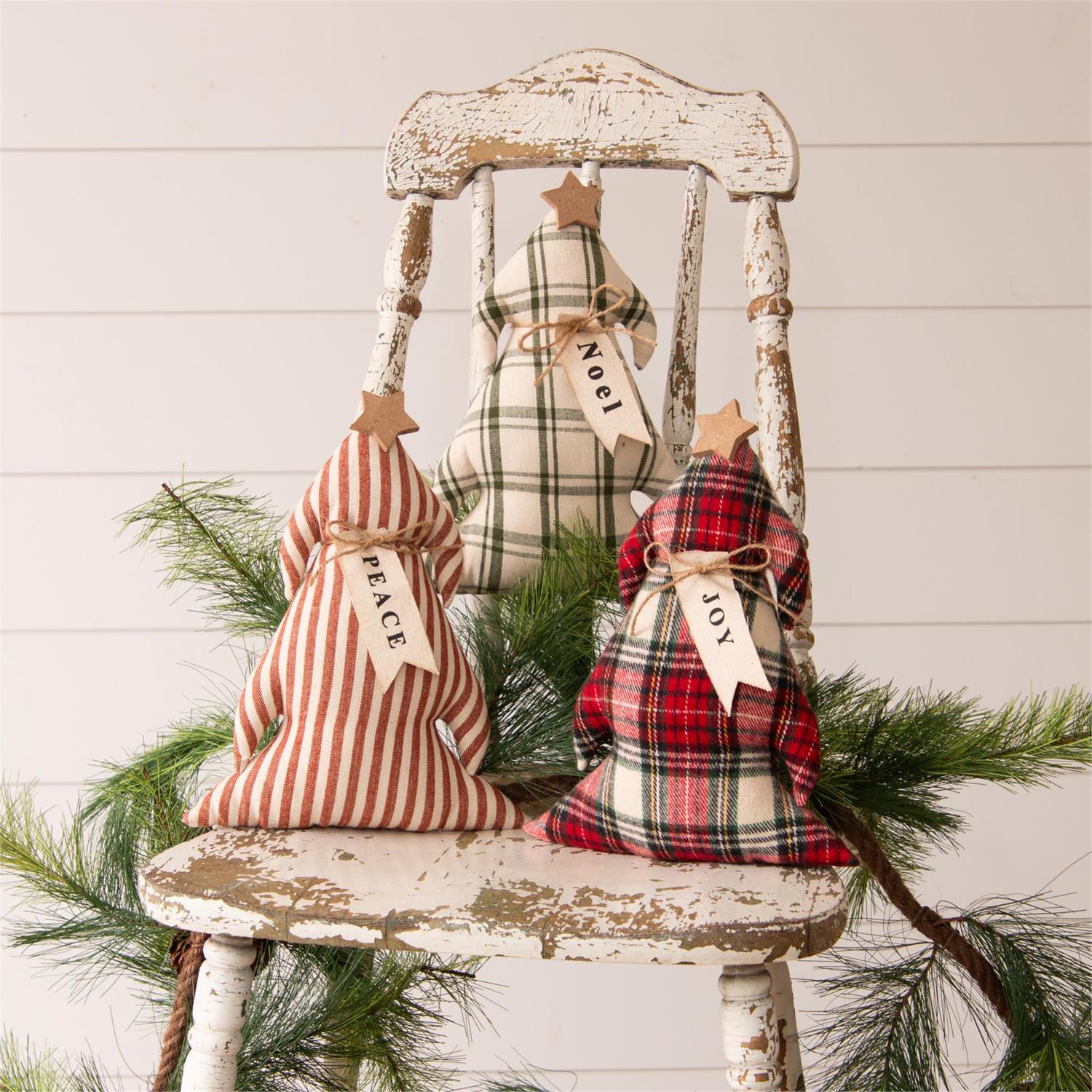 Decorative Christmas tree-shaped pillows on a rustic chair with evergreen branches.
