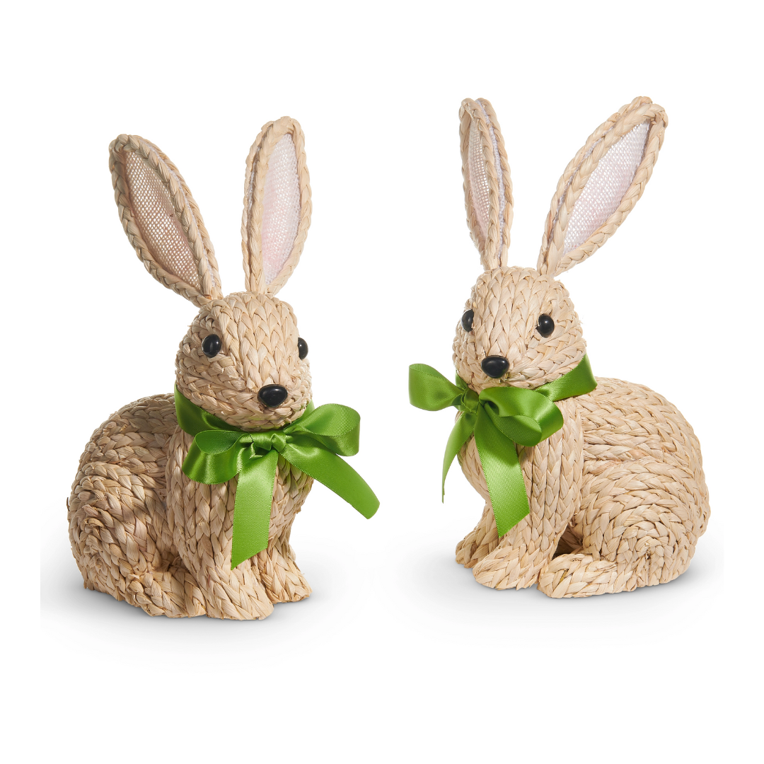 Two woven rabbit figurines with green bows on a white background
