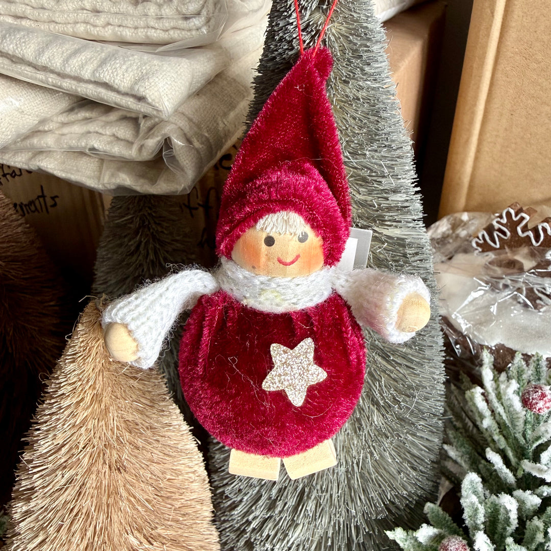 Decorative boy ornament with red hat and star on a Christmas tree.