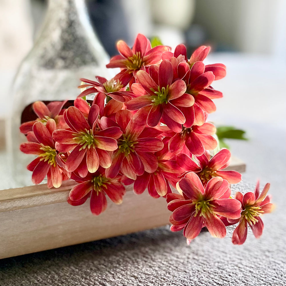 A set of three artificial orange chrysanthemum sprays placed on a surface, depicting realistic touch and vibrant color.