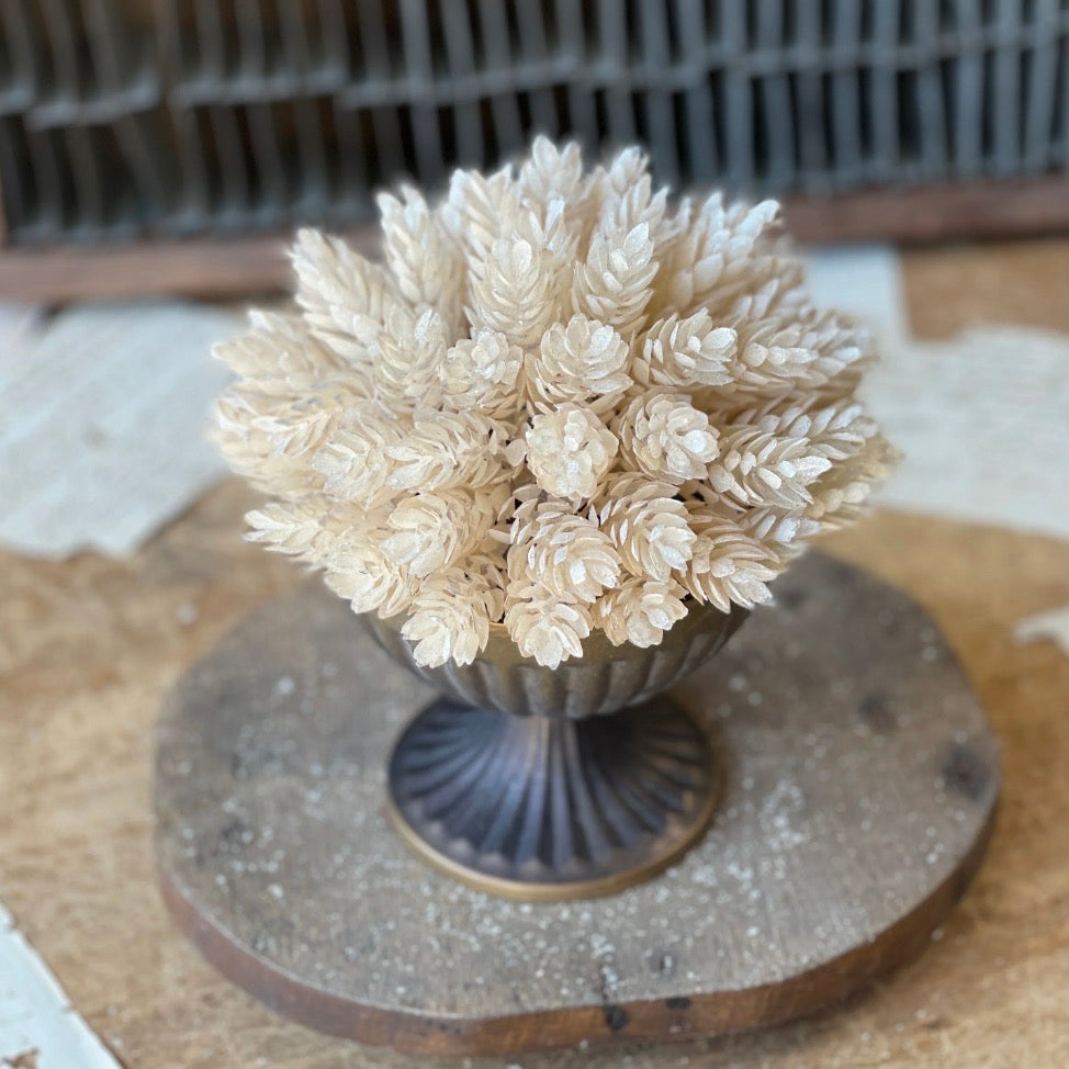 A artificial pearl hops half sphere with a light pearl-leaf finish, dusted with ultra fine glitter, displayed on a wooden stand.